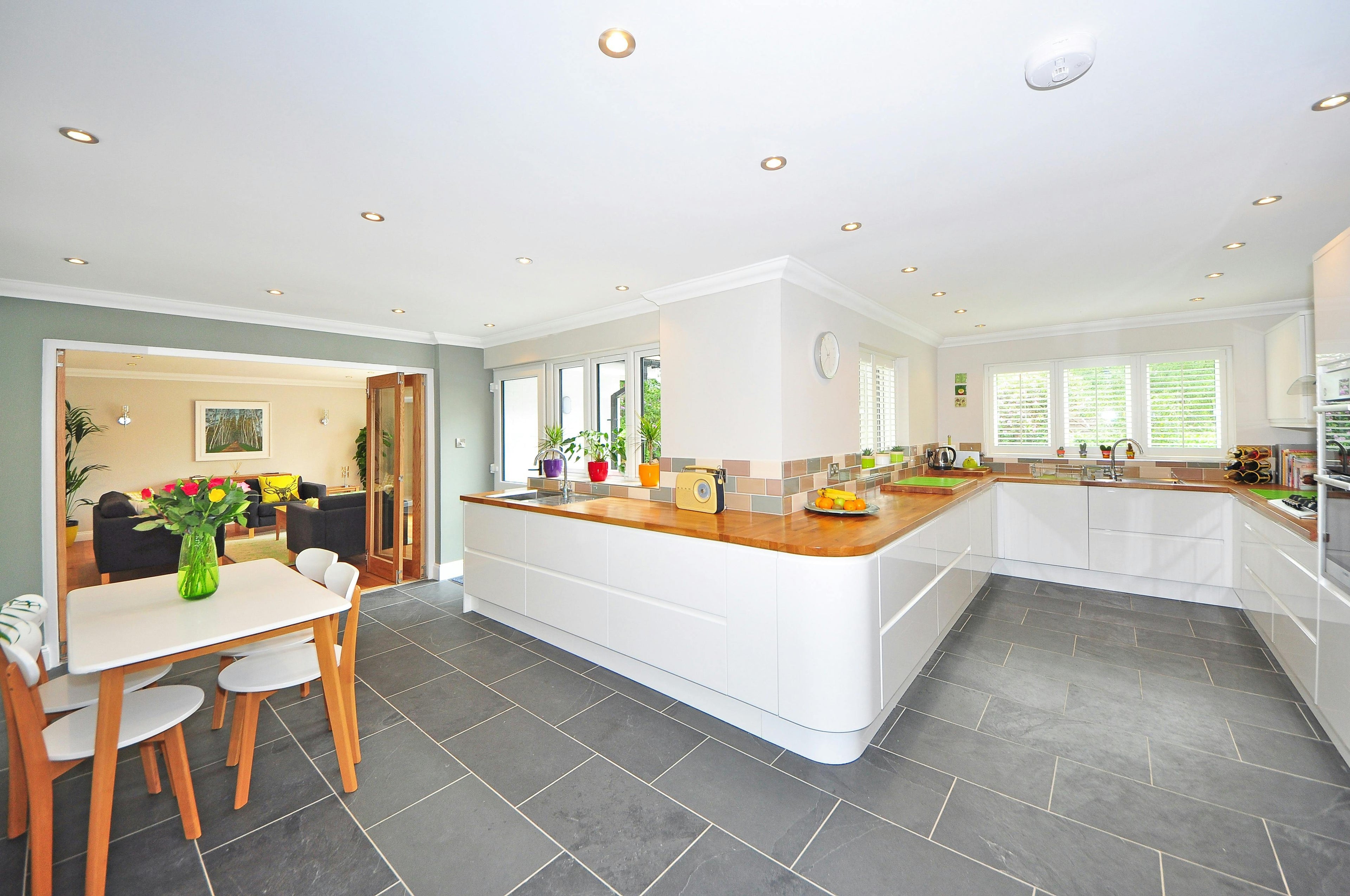 Modern kitchen with white cabinets, wooden countertops, and a dining area by Casa Duah