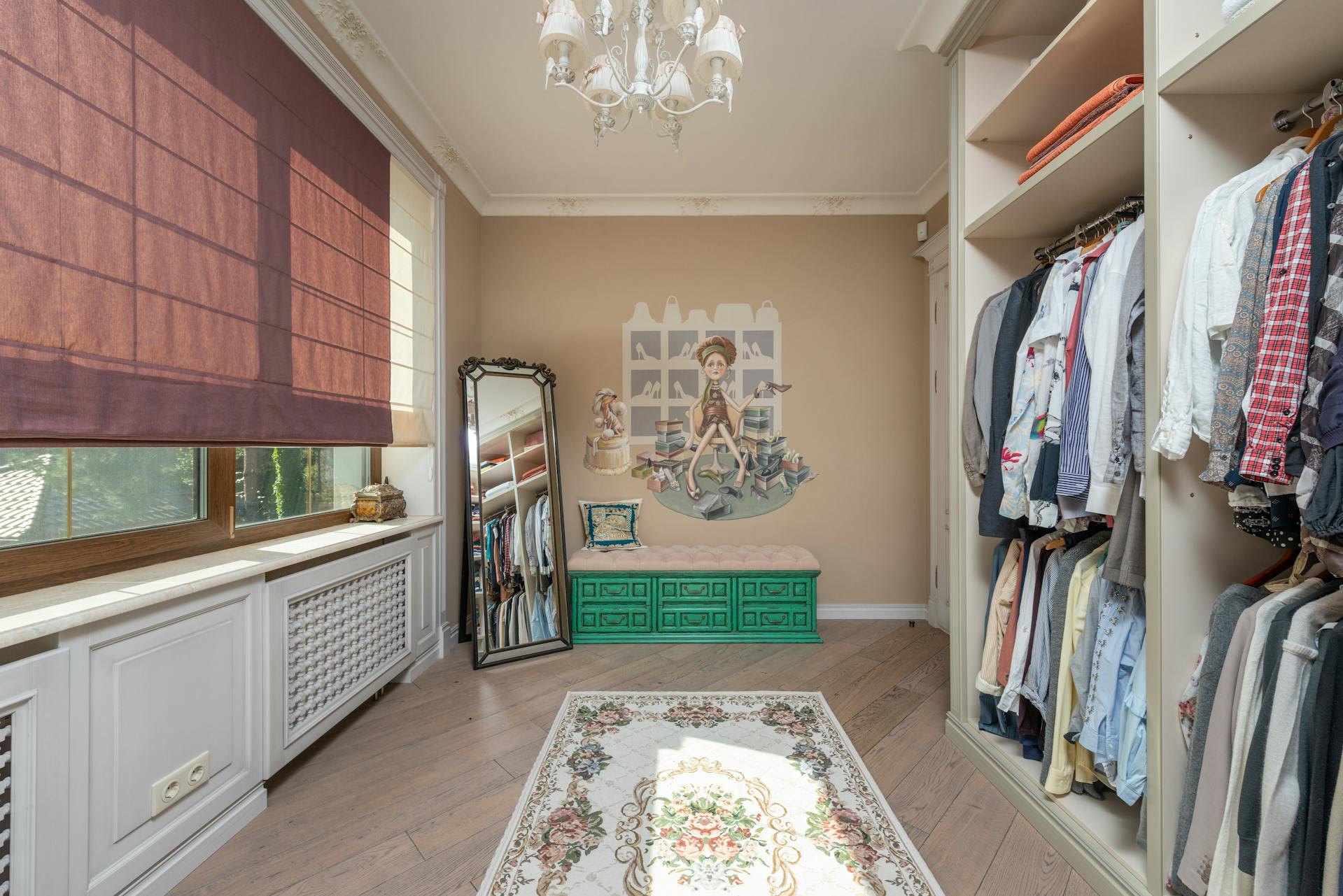 Walk-in closet with clothes on racks, a chandelier, and decorative elements by Casa Duah